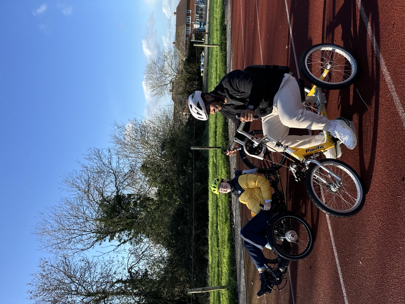 A client riding an adapted cycle outdoors during a community rehabilitation session